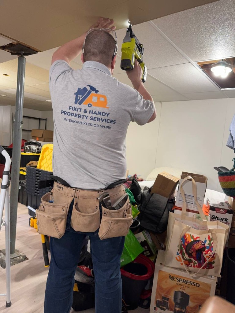 Craftsman in branded shirt cutting trim with snips, floor covered for a clean job site.